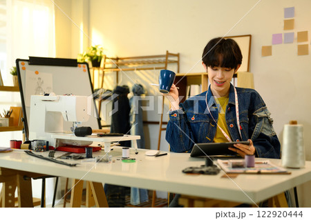 Designer holding a cup of coffee and using digital tablet in a creative studio 122920444