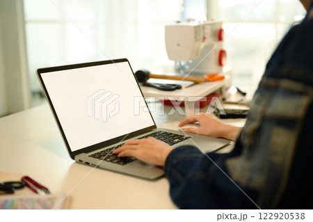 Young designer working on laptop planning their next collection in a modern workspace 122920538