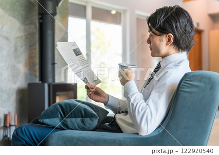 朝家で英字新聞を読むスーツ姿のアジア人ビジネスマン 122920540