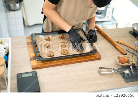Baker preparing chocolate chip cookie dough on a baking tray Baker preparing chocolate chip cookie dough on a baking tray 122920556