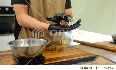 Cropped shot man rolling ball of chocolate chip cookie dough, preparing it for baking 122920563