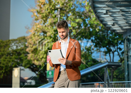 Portrait of young businessman wearing stylish suit using digital tablet outside office building Portrait of young businessman wearing stylish suit using digital tablet outside office building 122920601