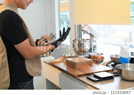 Home baker wearing gloves before handling ingredients while baking cookies 122920687