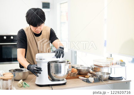 Asian male baker using a stand mixer to prepare cookie dough 122920716