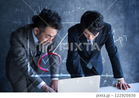 スーツを着た2人のビジネスマンとパソコンを見て広告やマーケティングを考える 122920830