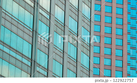 A close-up of modern architecture showcasing contrasting glass facades, blending blue and beige tones with clean geometric patterns. A close-up of modern architecture showcasing contrasting glass facades, blending blue and beige tones with clean geometric patterns. 122922757