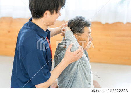 リハビリで体操をするシニア男性と理学療法士・作業療法士の男性スタッフ 122922898