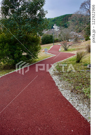 公園内の歩道を新しくエンジ色に舗装し直した風景 122922966