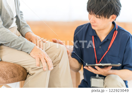 シニア男性にカウンセリングする理学療法士・マッサージ師のアジア人男性 122923049