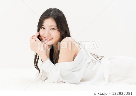 ビューティーイメージ　頬付を付いて笑顔で寝そべる若い女性 　カメラ目線 122923381