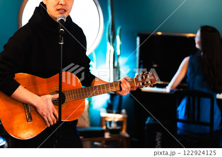 弾き語りで歌う男性とピアノを弾く女性 弾き語りで歌う男性とピアノを弾く女性 122924125