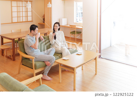 朝起きてリビングでコーヒーを飲む夫婦 122925122
