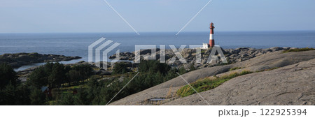 Red and white cast iron Eigeroy lighthouse, rock formations and ocean, Norway. 122925394