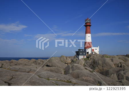 Red and white cast iron Eigeroy Lighthouse, rock formations and Nort Sea, Norway. Red and white cast iron Eigeroy Lighthouse, rock formations and Nort Sea, Norway. 122925395