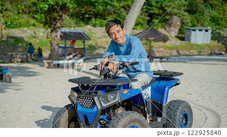 Young Man Enjoying ATV Ride on Sandy Beach Vacation Travel Adventure Young Man Enjoying ATV Ride on Sandy Beach Vacation Travel Adventure 122925840