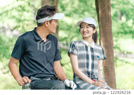 ゴルフ場でゴルフレッスンするゴルファーの男女(休憩・水分補給) ゴルフ場でゴルフレッスンするゴルファーの男女(休憩・水分補給) 122926216