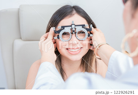 View of specialist checking vision of patient with trial frame in ophthalmology clinic. Vision check with optometrist trial frame on patient View of specialist checking vision of patient with trial frame in ophthalmology clinic. Vision check with optometrist trial frame on patient 122926291