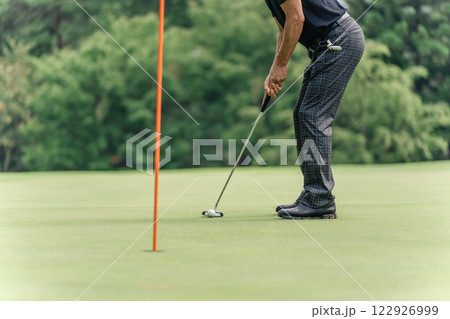 ゴルフ場のカップにパターを使ってカップインしようとする男性ゴルファー ゴルフ場のカップにパターを使ってカップインしようとする男性ゴルファー 122926999