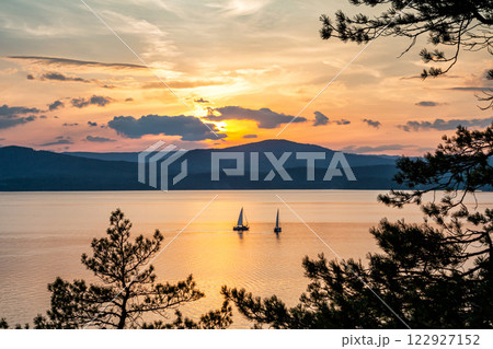 Two yachts on a picturesque lake against the backdrop of a picturesque sunset Two yachts on a picturesque lake against the backdrop of a picturesque sunset 122927152
