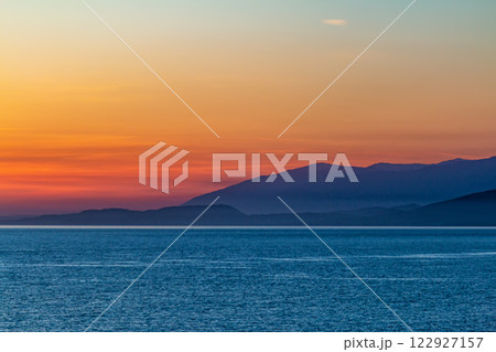 Scenic sunrise on the ocean with mountain views Scenic sunrise on the ocean with mountain views 122927157