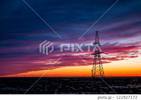Silhouette of a power line in a field against the backdrop of a picturesque sunset 122927172