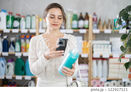 Young woman scanning QR-code on shampoo in department store 122927521