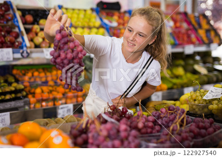 Teen shopper chooses grape at grocery store Teen shopper chooses grape at grocery store 122927540