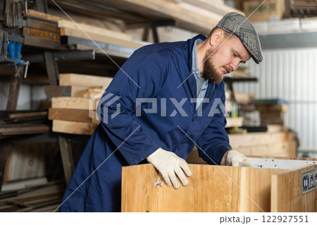Young man assembling wooden cabinet in workshop Young man assembling wooden cabinet in workshop 122927551