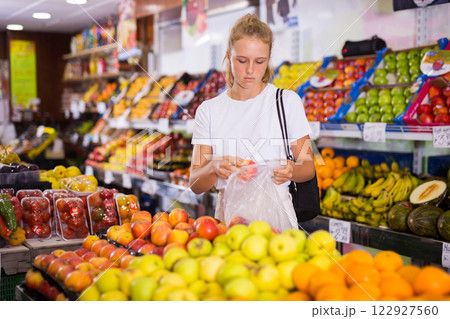 Fifteen-year-old girl chooses apples on the counter 122927560