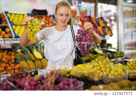 Teen shopper chooses grape at grocery store Teen shopper chooses grape at grocery store 122927571