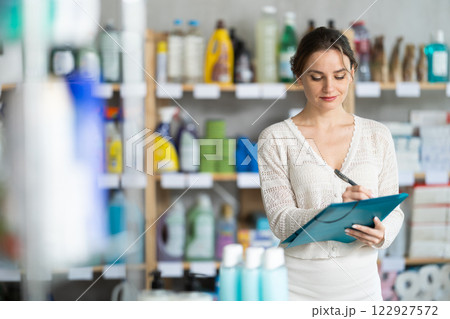 Young woman taking record of inventory in household store Young woman taking record of inventory in household store 122927572