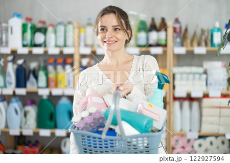 Woman with filled basket wanders around store, looking at display cases, seek something at counter Woman with filled basket wanders around store, looking at display cases, seek something at counter 122927594
