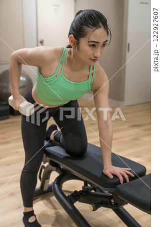 室内のジムで筋トレをする若い女性 122927607