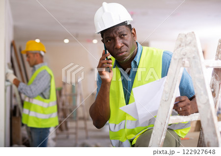 Man builder having telephone conversation in construction site Man builder having telephone conversation in construction site 122927648