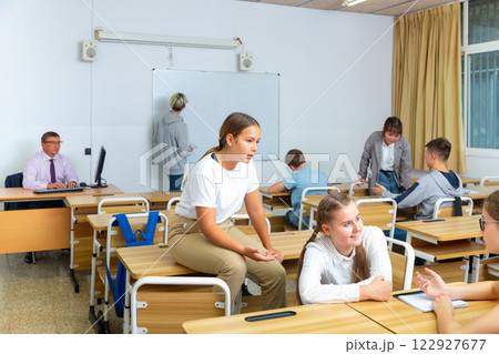 Teen students communicating during recess in classroom 122927677