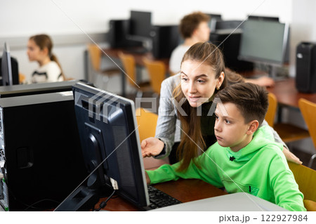 Teacher helping boy to solve computer problem Teacher helping boy to solve computer problem 122927984