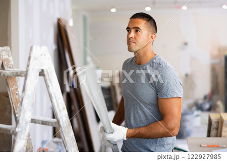 Young man holds an aluminum profile for interior decoration Young man holds an aluminum profile for interior decoration 122927985