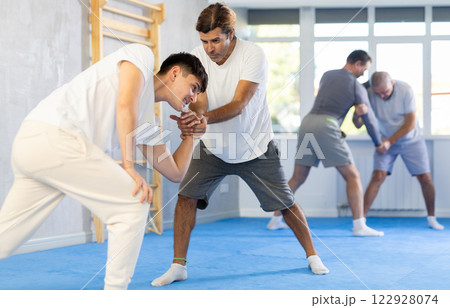 Guy and man are training in gym practicing palm grab technique 122928074