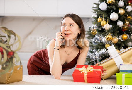 Attractive woman is preparing presents and discussing it with someone on a mobile phone Attractive woman is preparing presents and discussing it with someone on a mobile phone 122928146