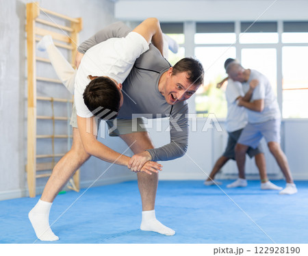 Young guy and man practice wrestling, apply techniques of Aikido and self-defense. 122928190