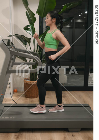 ジムでトレーニングウェアを着てランニングマシンで走る若い女性 122928208