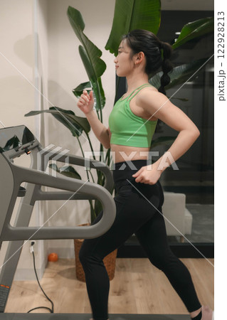 ジムでトレーニングウェアを着てランニングマシンで走る若い女性 ジムでトレーニングウェアを着てランニングマシンで走る若い女性 122928213