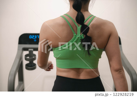 ジムでトレーニングウェアを着てランニングマシンで走る若い女性 122928219