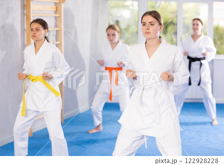Teenage girl with group in kimonos performing kata to hone martial arts skills 122928228