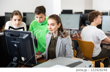 Female teacher and teenager pupils looking at monitor of PC Female teacher and teenager pupils looking at monitor of PC 122928248