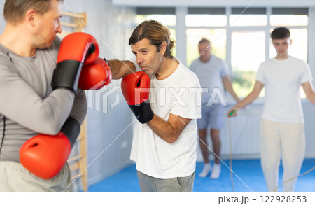 Men in boxing gloves punch deliver blow each other during training sparring session. Men in boxing gloves punch deliver blow each other during training sparring session. 122928253