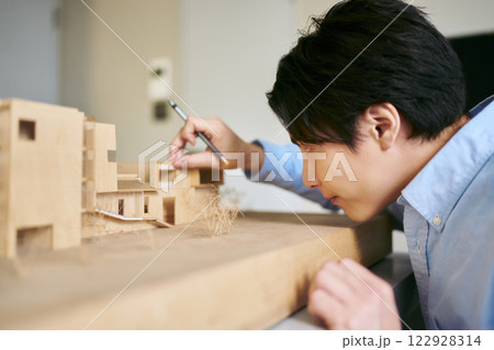 設計のコンペディションの為の建築模型を真剣に想像力を働かせて作る1人の男性 設計のコンペディションの為の建築模型を真剣に想像力を働かせて作る1人の男性 122928314