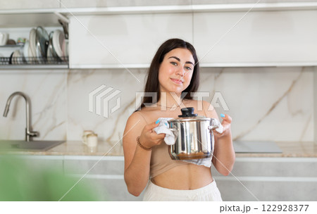 Young woman posing with saucepan in kitchen at home Young woman posing with saucepan in kitchen at home 122928377