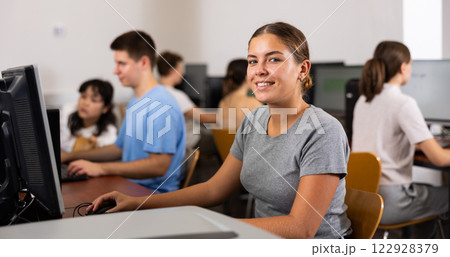 Positive female student smiling, using PC and studying computer science in the classroom Positive female student smiling, using PC and studying computer science in the classroom 122928379