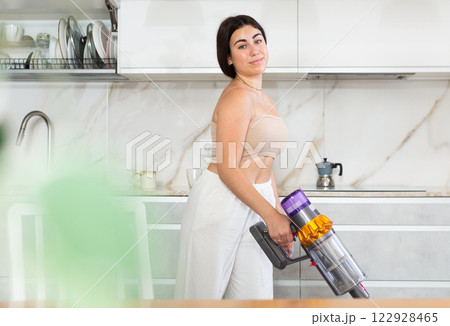 Young woman vacuuming floor in kitchen at home Young woman vacuuming floor in kitchen at home 122928465